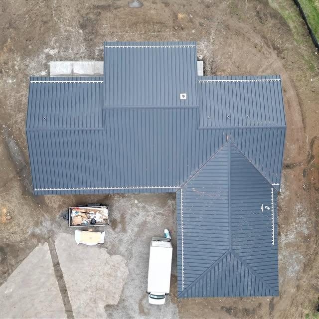 Top-down drone view of a dark gray standing seam metal roof