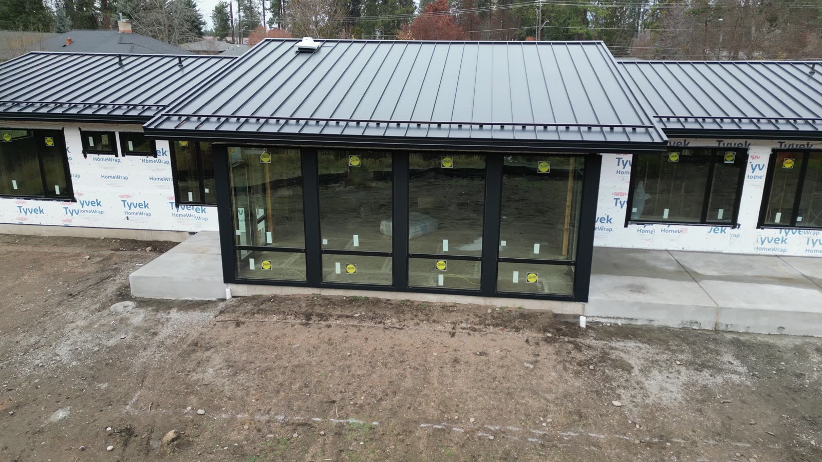 Black standing seam metal roof over a wall of windows on a new home